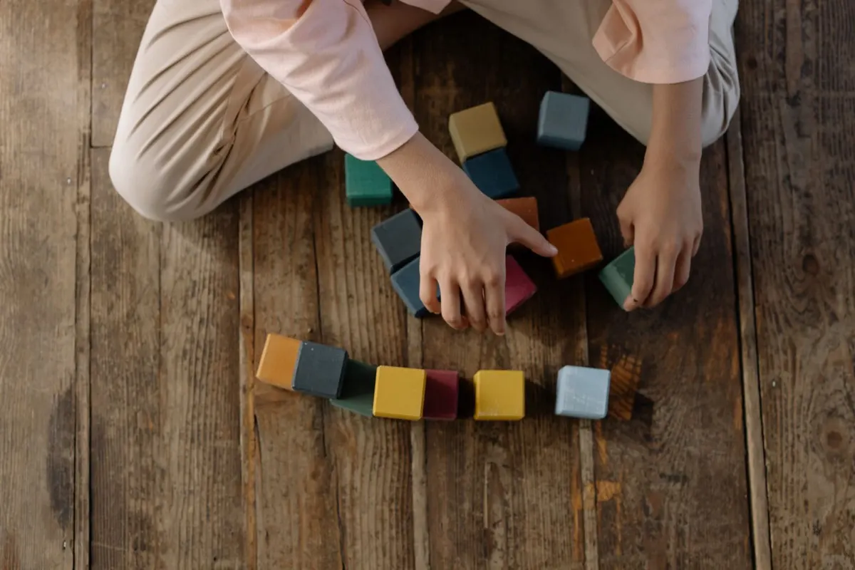 A young child playing with wooden building blocks on the floor