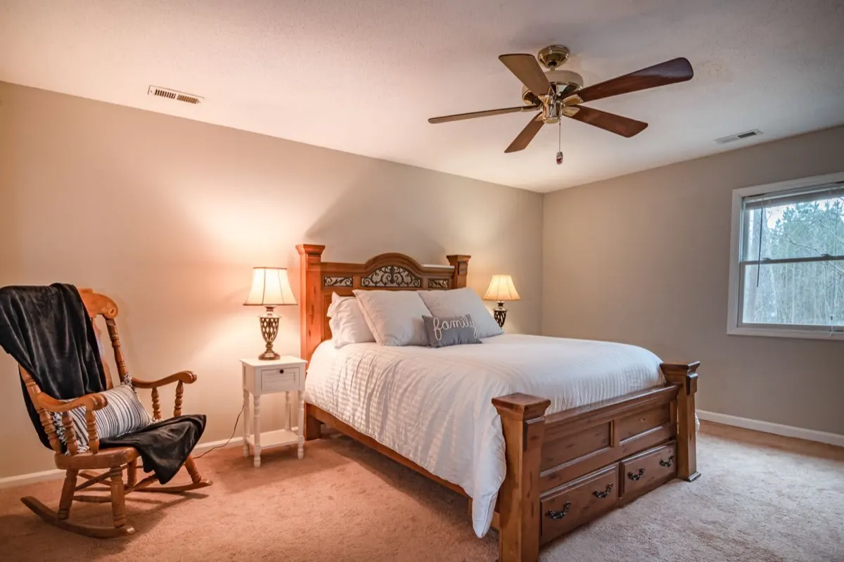A warm private bedroom with a wooden bed and reading chair