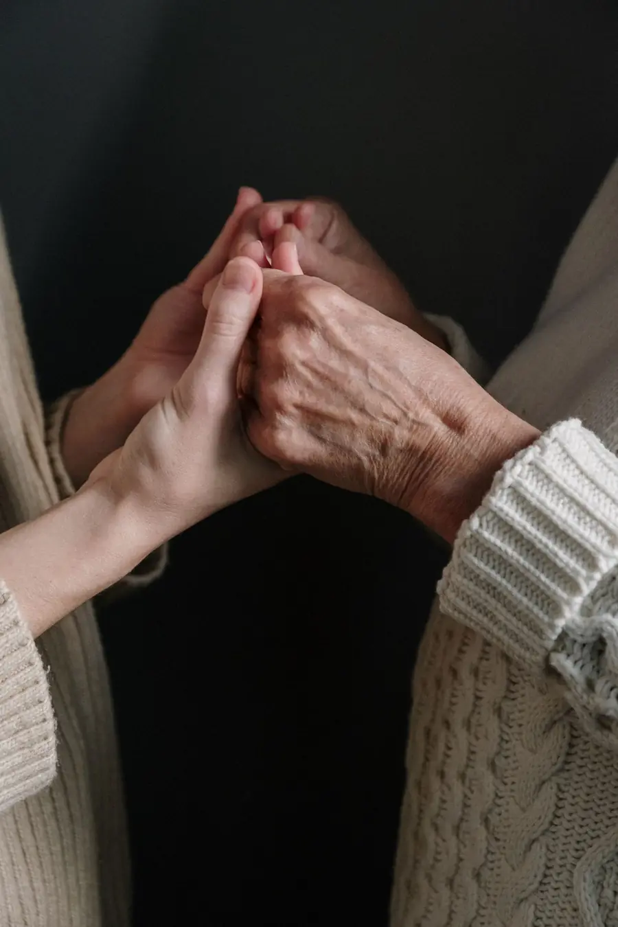 Younger hands gently holding an older person's hand